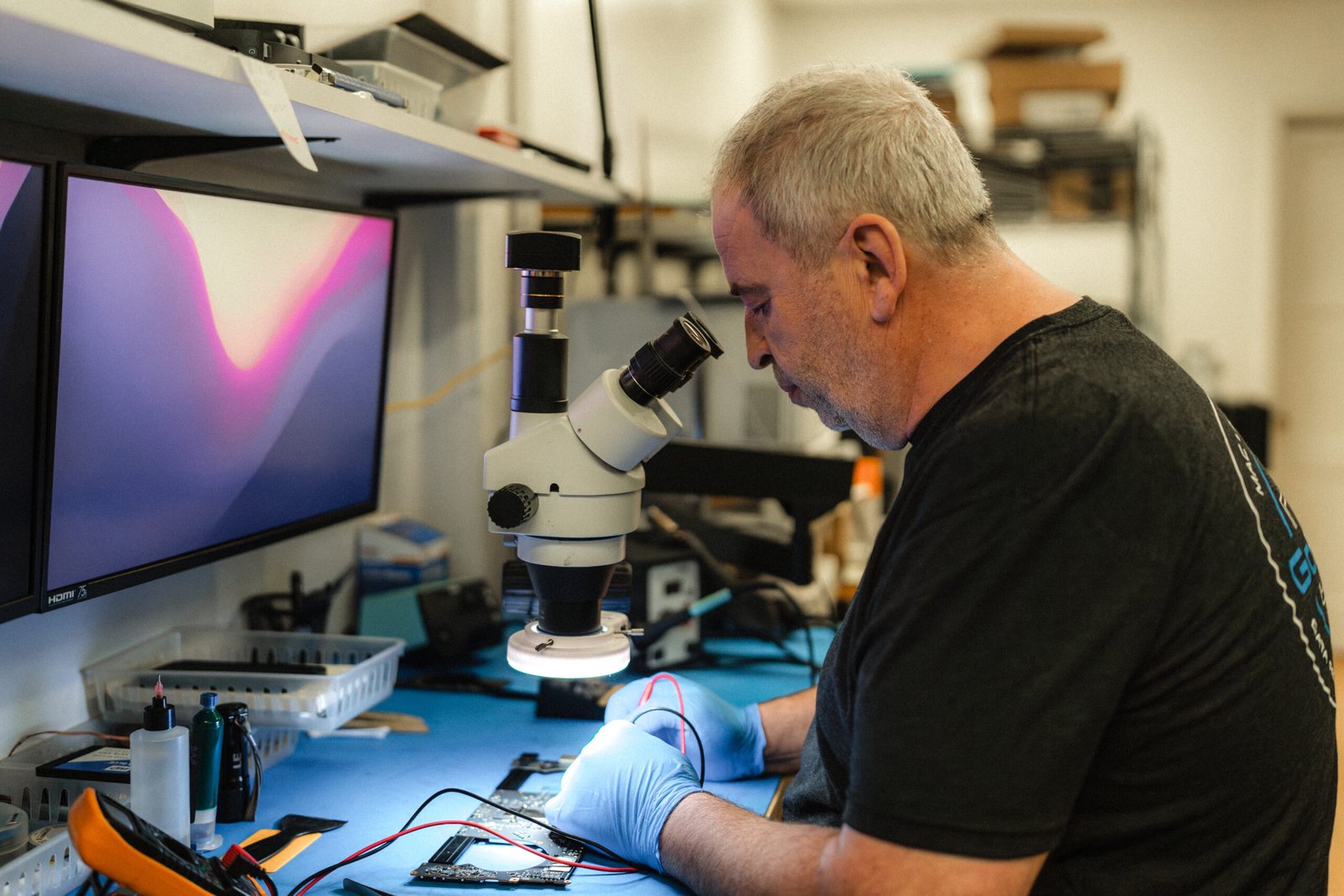 phone and computer repair shop with technician working on a motherboard logic board